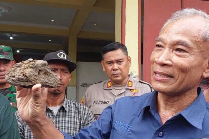 Prof Basuki Rahmad saat menunjukan batuan berwarna gelap yang diambil sebagai sampel (Sumber: kompas.com)